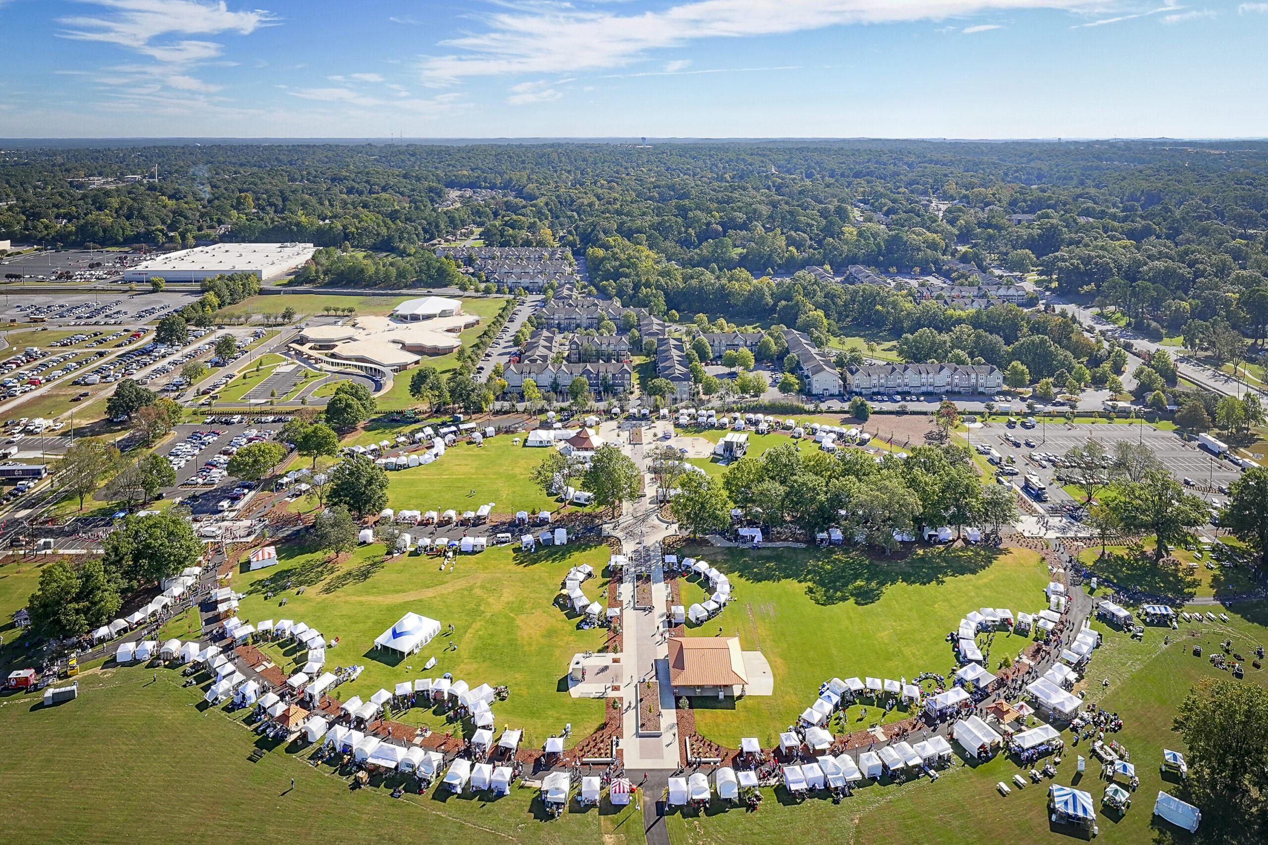 Drone photo of Snow Hinton Park shows white Kentuck Arts Festival tents lining oval path